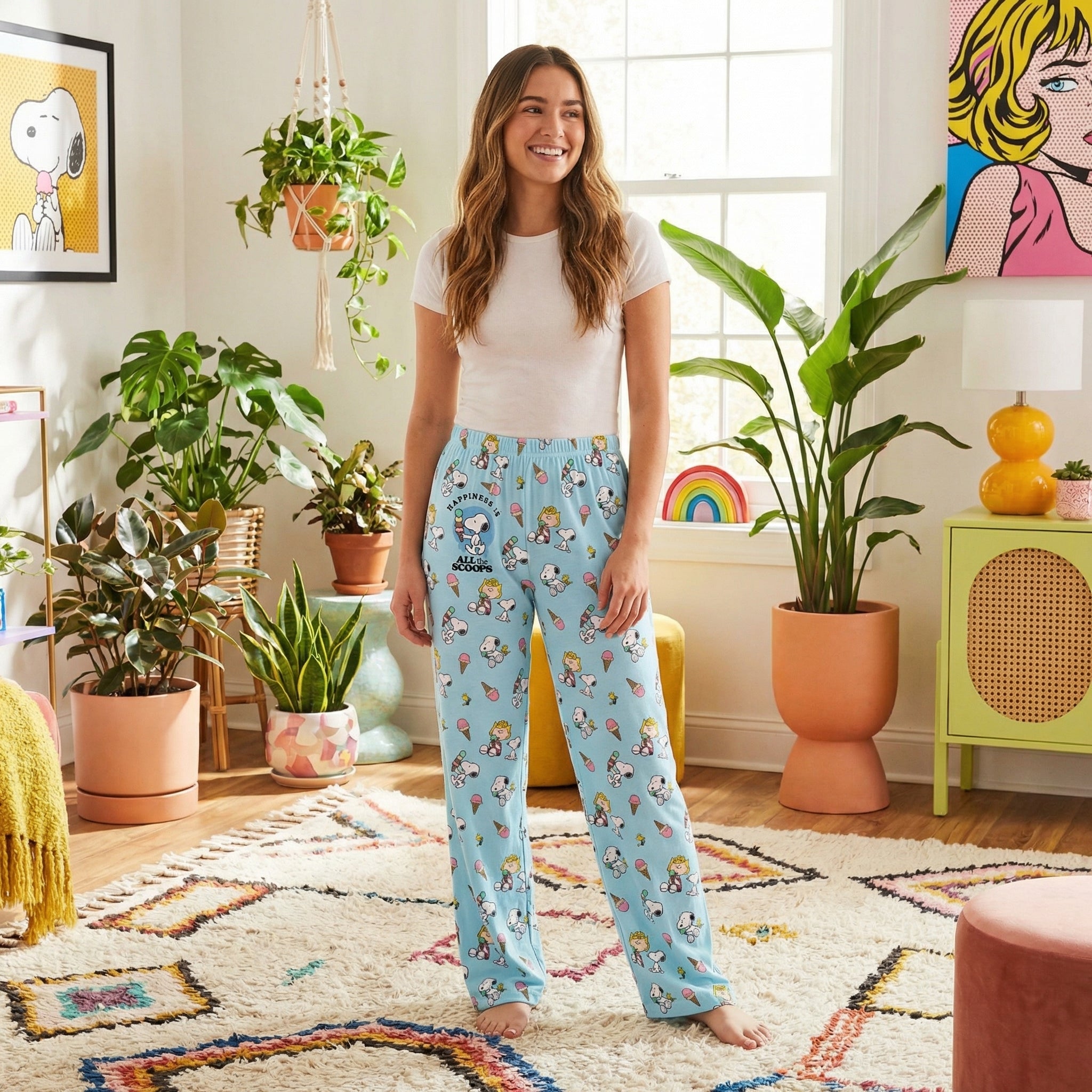 Young female model in colorful living room wearing Snoopy ice cream lounge pants, relaxed with playful vibe.