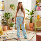 Young female model in colorful living room wearing Snoopy ice cream lounge pants, relaxed with playful vibe.