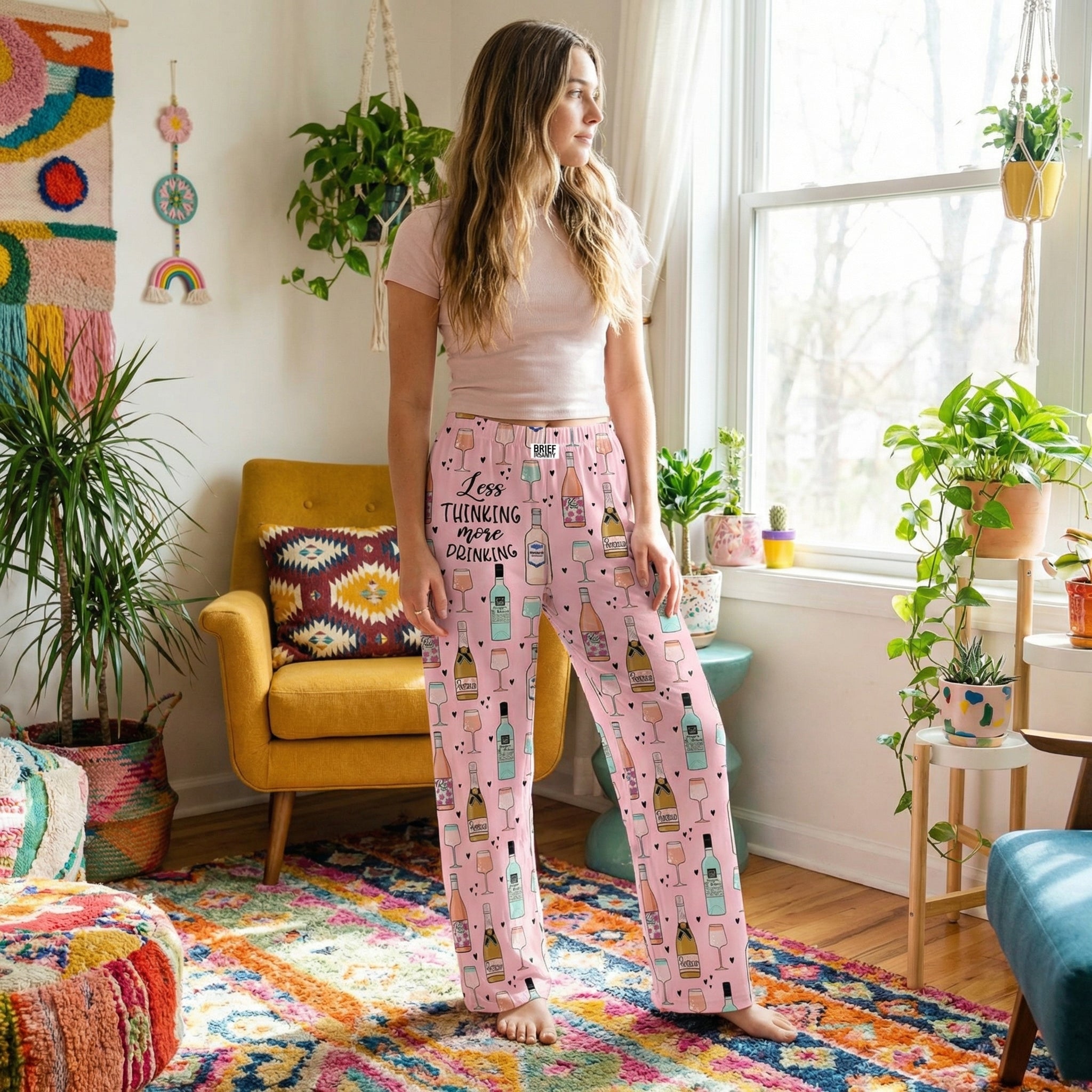 Lifestyle scene with young woman in light pink lounge pants in a colorful living room, surrounded by decor and plants, relaxed pose.
