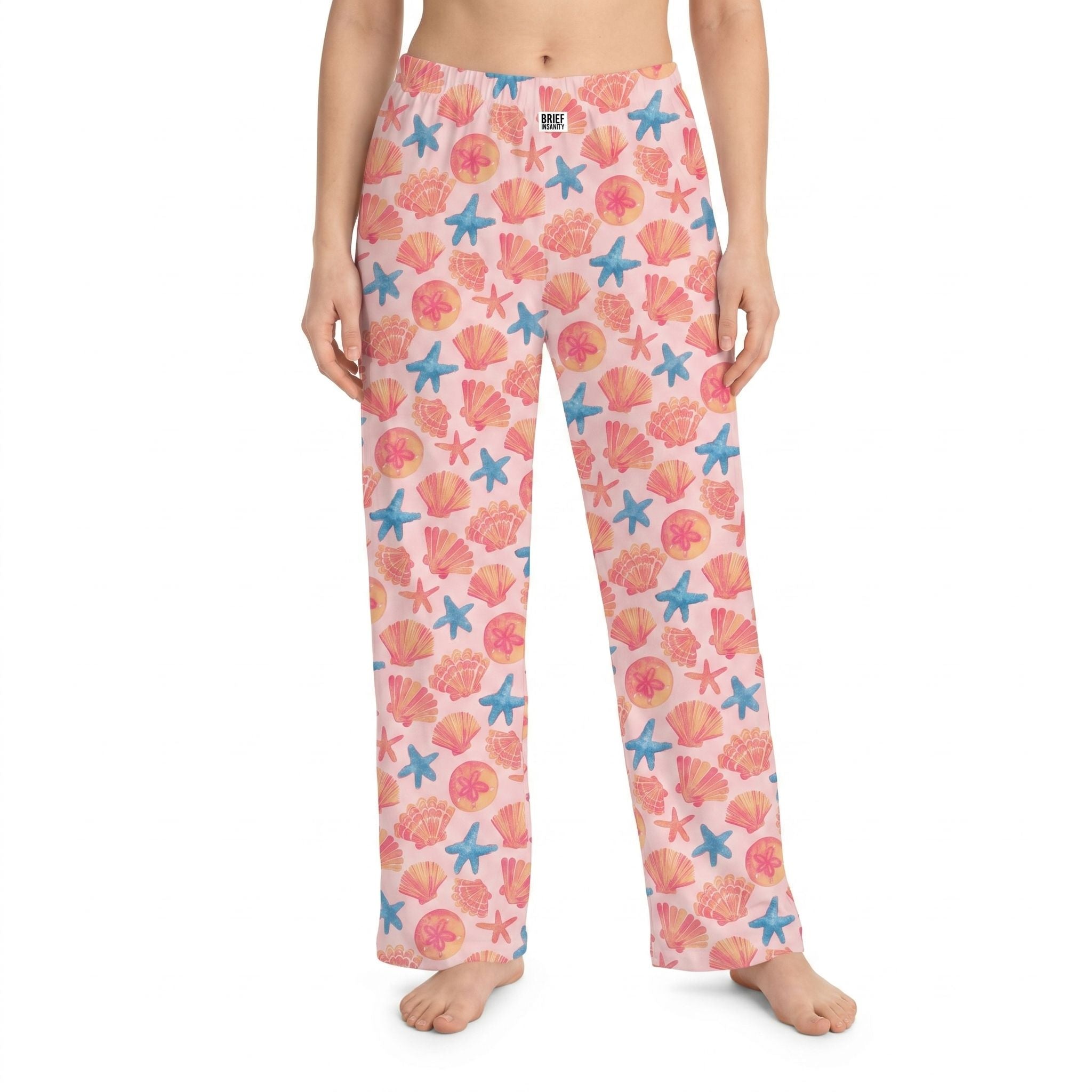 High-resolution image of orange seashells lounge pants on a model against a white background, showcasing vibrant coastal print and fabric details.