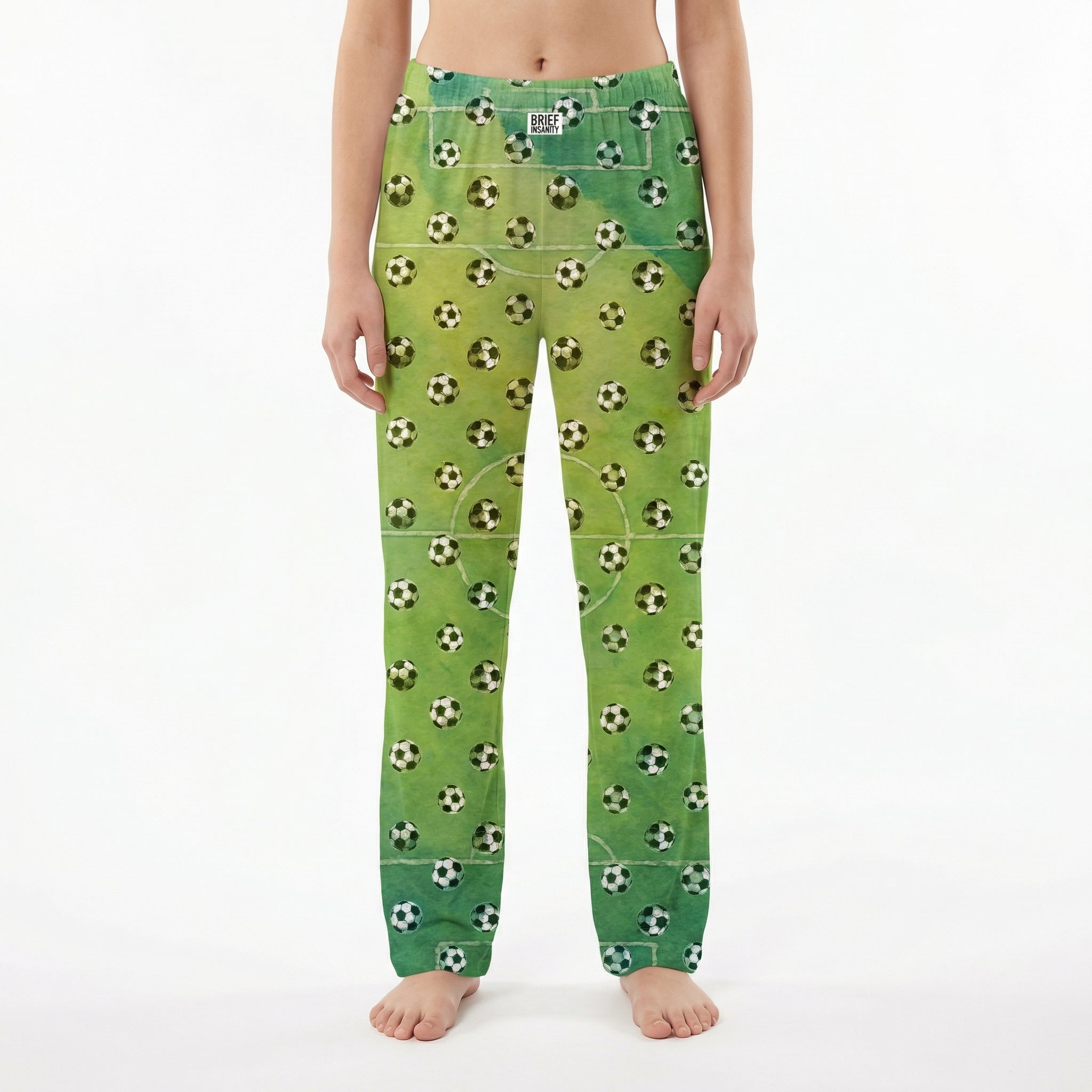 Young female model wearing soccer lounge pants with soccer ball print on white background.