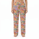 Model wearing vibrant desert landscape lounge pants against white background, fully visible, cropped from waist to ankles, showcasing print details.
