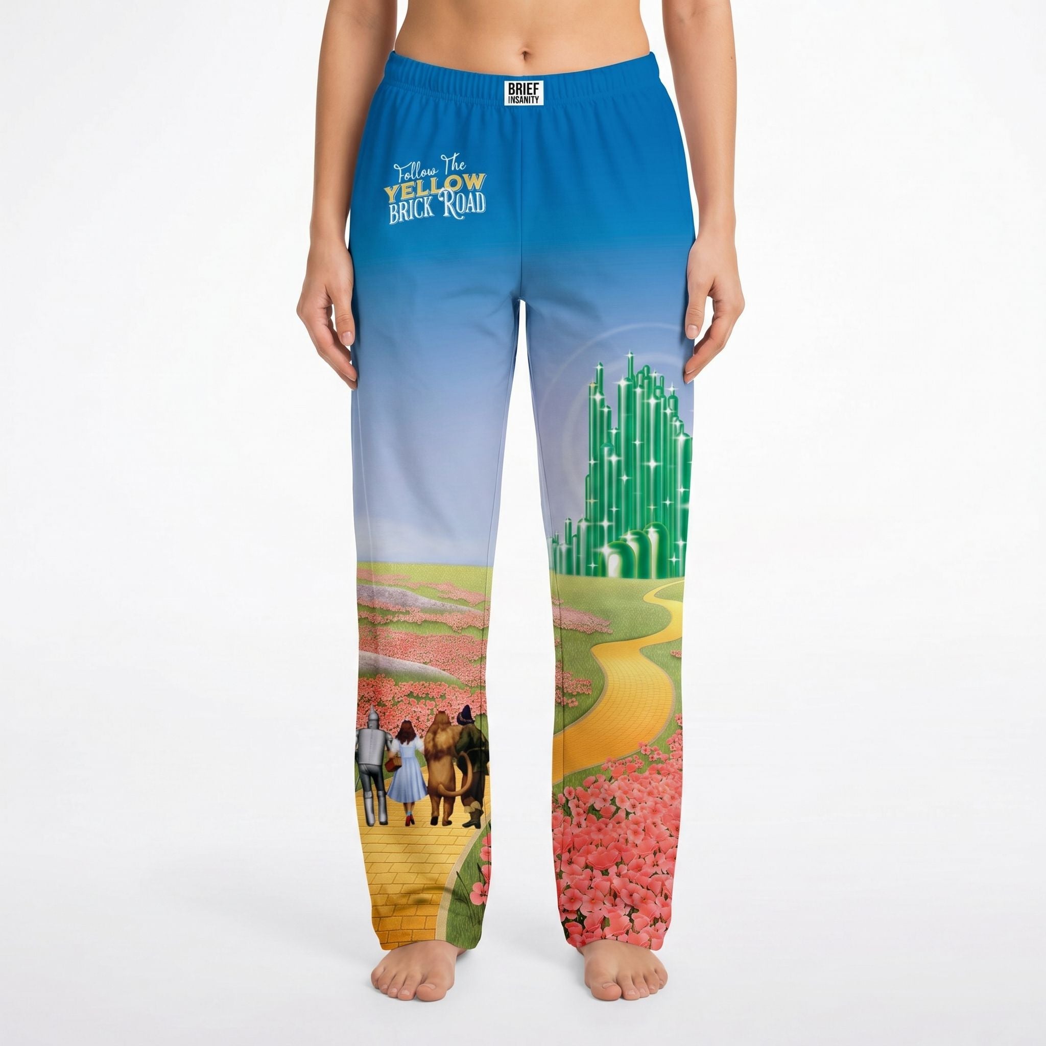 Female model wearing Wizard of Oz Emerald City lounge pants on white background, showcasing vibrant all-over print and relaxed fit.