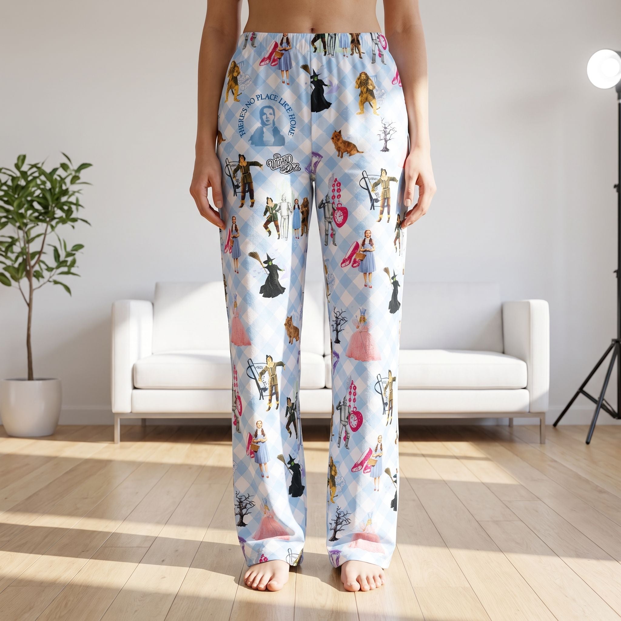 Woman wearing Wizard of Oz character print lounge pants with blue gingham plaid pattern in a modern living room.