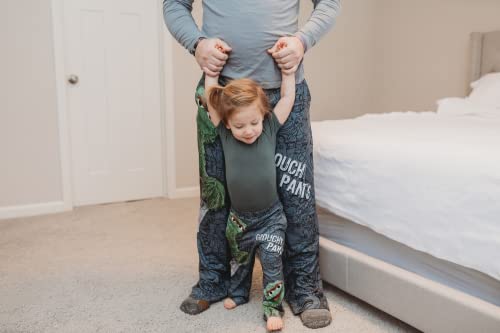 Image of dad model wearing Sesame Street Oscar The Grouch pajama lounge pants facing forward holding hands of daughter model who's standing in front of him who's also wearing Sesame Street Oscar The Grouch pajama lounge pants (kids version)