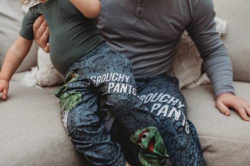 Close up image of dad model with daughter model on lap sitting on a gray couch wearing Sesame Street Oscar The Grouch pajama lounge pants