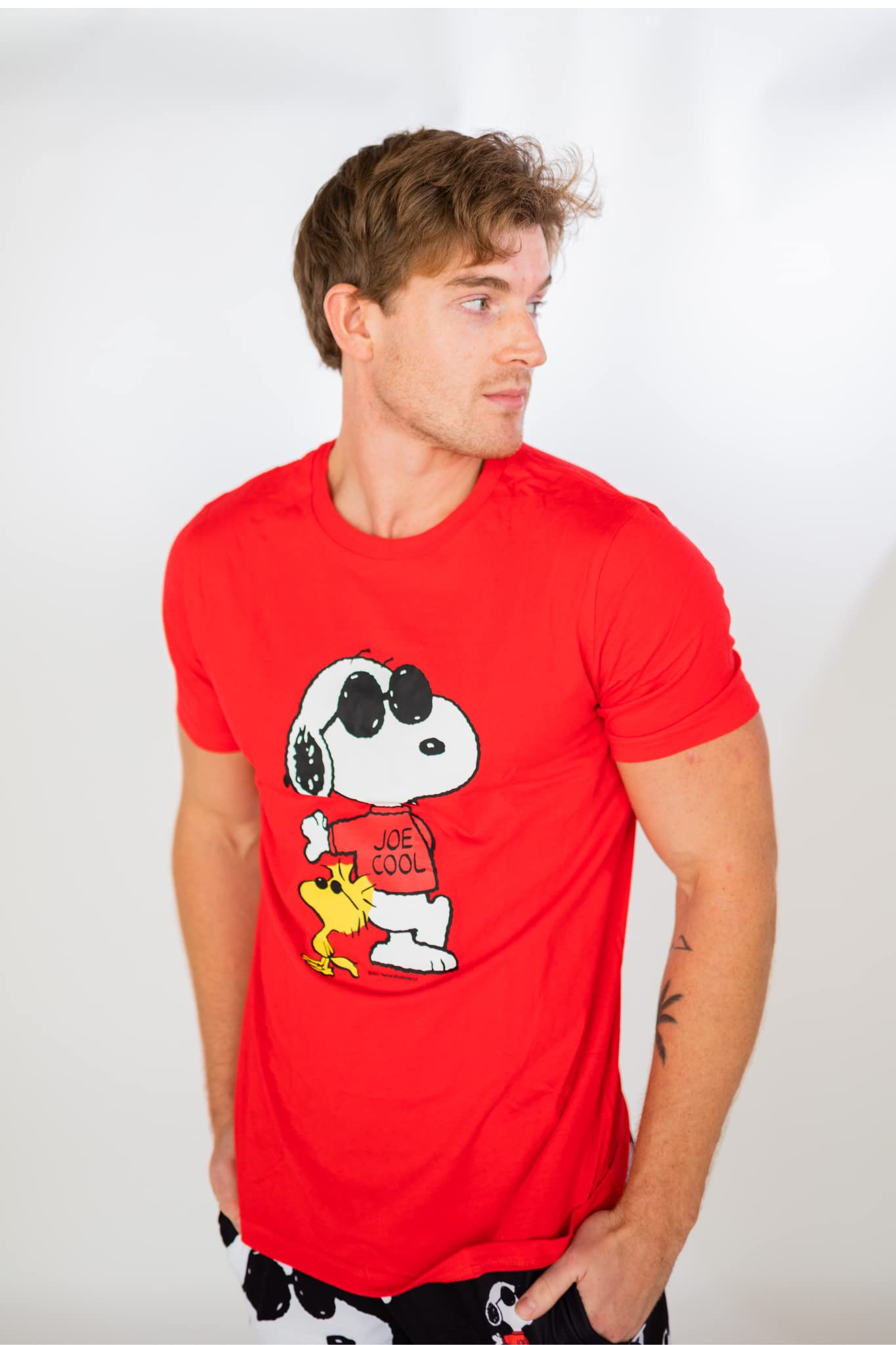 Image of male model standing and looking off into the distance wearing Peanuts Snoopy Joe Cool short sleeve T-shirt (front view white background)