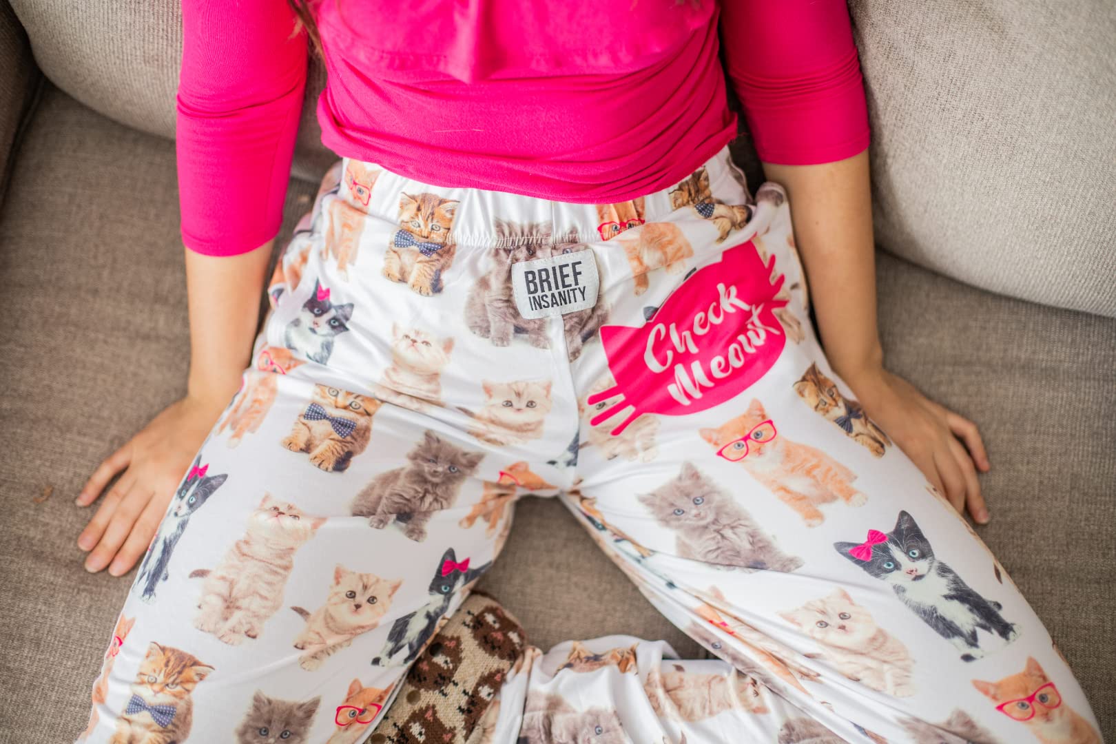 Birds eye view image of model sitting on couch wearing Check Meowt pajama lounge pants
