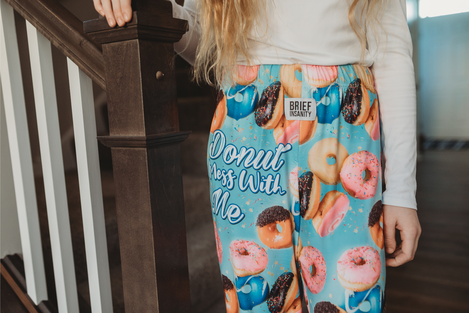 Close up image of girl model standing by the end of stairs wearing Donut Mess With Me pajama lounge pants (front view)