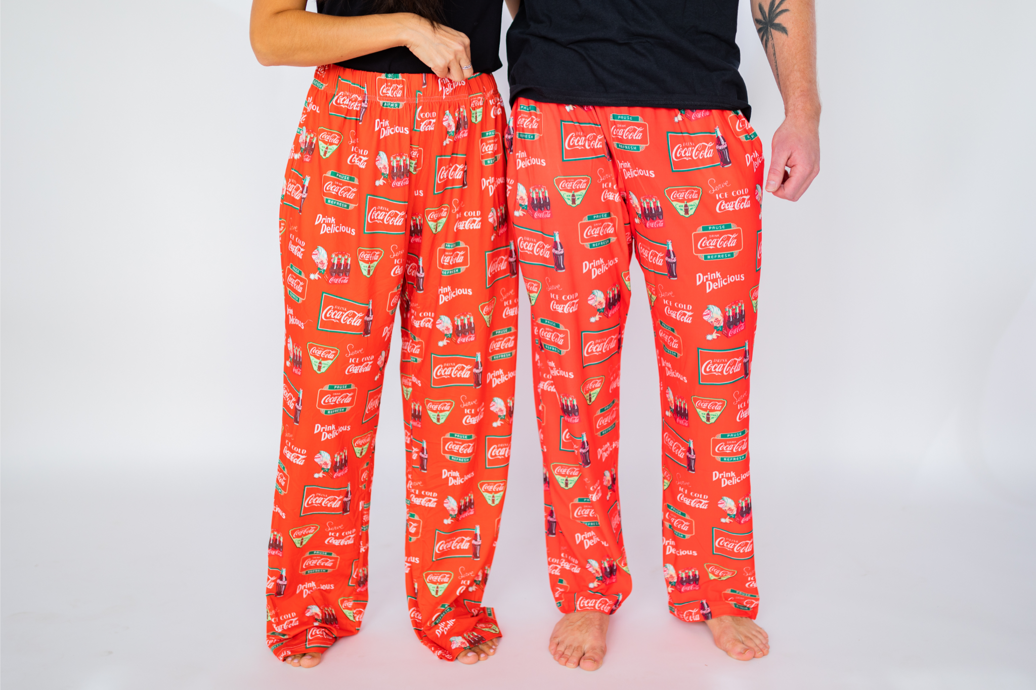 Waist down image of female model and male model standing next to each other (front view) wearing the Coca-Cola Retro Pattern pajama lounge pants