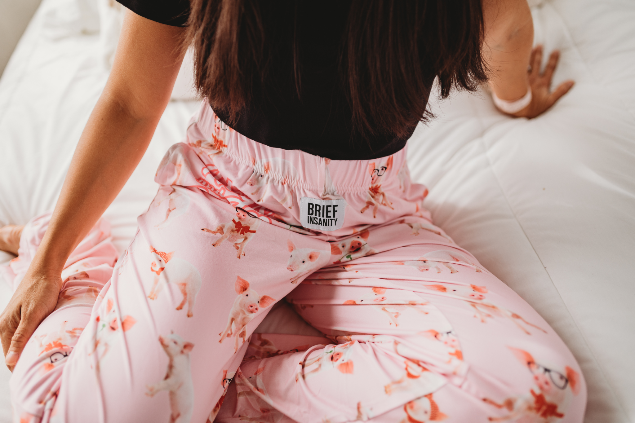 Close up of female model sitting on bed wearing Hogs And Kisses pajama lounge pants
