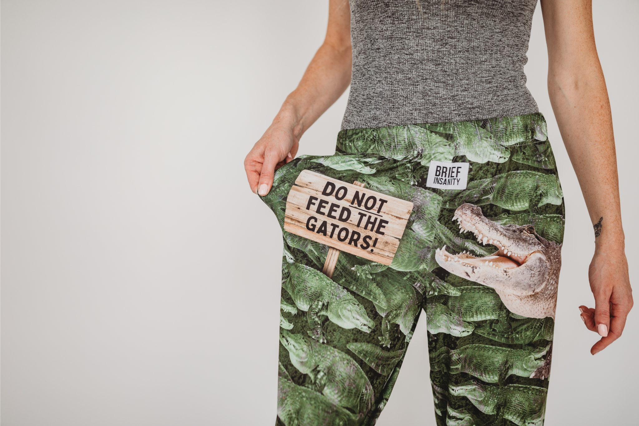 Cropped close up image of model wearing Do Not Feed The Gators pajama lounge pants front view showing off text (white background)