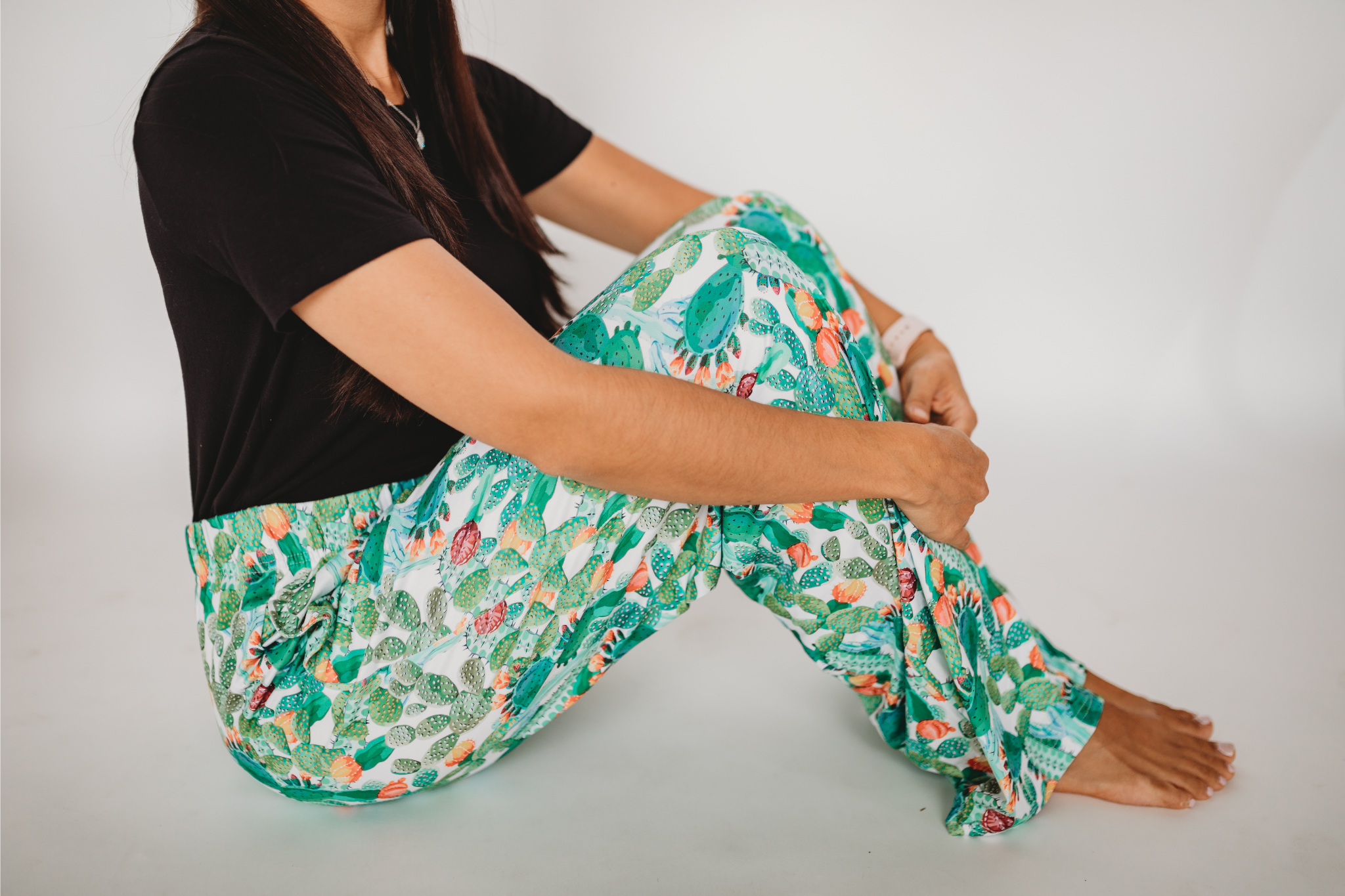 Waist down photo of model sitting on the floor sideways with knees up wearing Floral Cactus pajama lounge pants
