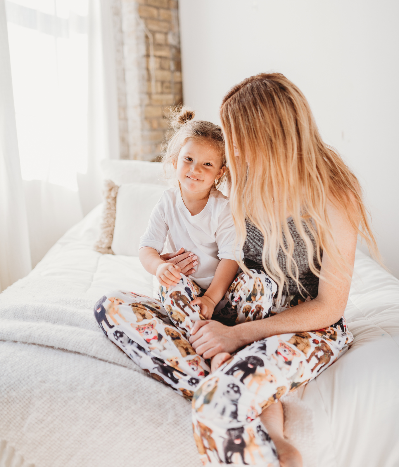 Image of mom model sitting on bed wearing I Ruff You pajama lounge pants holding daughter model wearing I Ruff You pajama lounge pants kids version (front view)