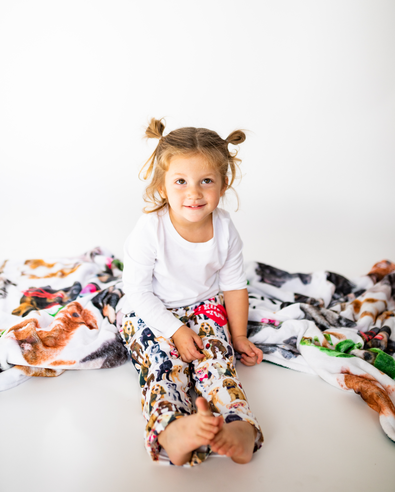 Toddler wearing Briefly Kids I Ruff You Pajama Lounge Pants and sitting on a cozy Life is Better with a Dog Throw Blanket